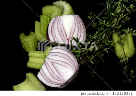 Close up of chopped celery onion and rosemary waiting to be used to cook dinner on a black background 132129351
