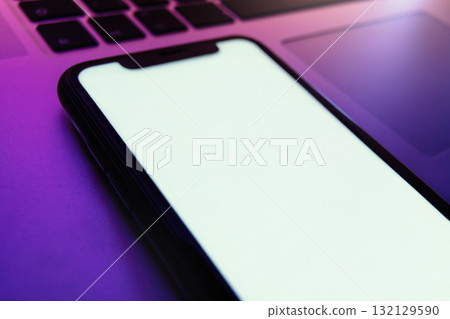 Mock up, modern smartphone with blank white screen lies on laptop 132129590