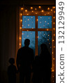 Silhouette of family of four standing by a window at dusk, looking outside 132129949