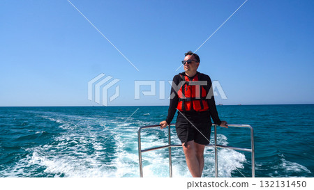 A Scenic Day on the Water: A Leisurely Cruise with a Relaxed Individual Enjoying the Beautiful Ocean View on a Bright Sunny Day 132131450