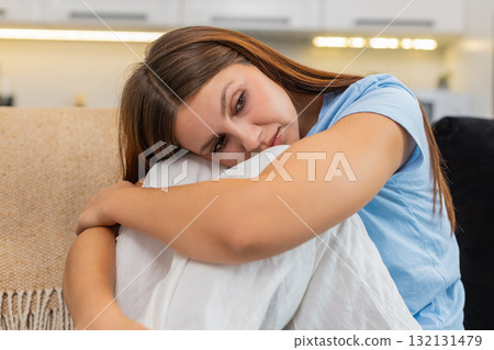 Young woman curls up arms around legs sad stressed after bad day seeks comfort silent and calm peace 132131479