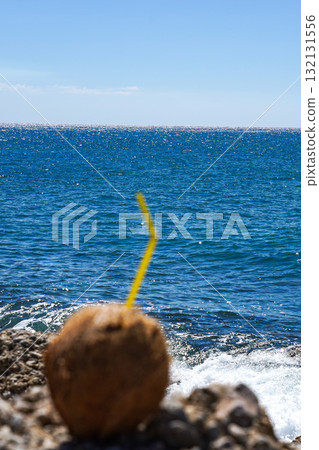 Refreshing Coconut Drink by the Sparkling Ocean Waves under a Clear Blue Sky, Perfect for a Tropical Escape and Summer Relaxation Refreshing Coconut Drink by the Sparkling Ocean Waves under a Clear Blue Sky, Perfect for a Tropical Escape and Summer Relaxation 132131556