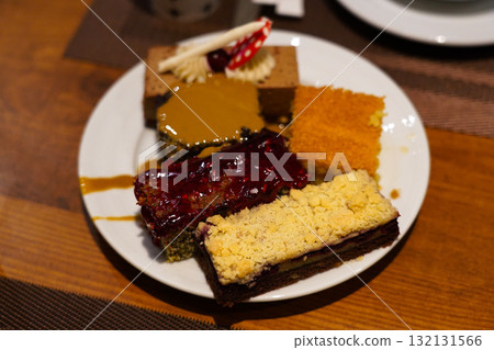 A Delightful Assortment of Colorful Cakes on a Plate, Showcasing Various Flavors and Textures with Rich Toppings and Creamy Layers to Tempt Every Sweet Tooth A Delightful Assortment of Colorful Cakes on a Plate, Showcasing Various Flavors and Textures with Rich Toppings and Creamy Layers to Tempt Every Sweet Tooth 132131566