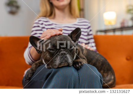 Middle-aged woman with dog rests on knees gentle strokes comfort close bond warm touch caring mood Middle-aged woman with dog rests on knees gentle strokes comfort close bond warm touch caring mood 132131627