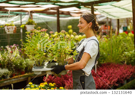 A Young Woman Engaged in Her Work at a Vibrant Garden Center Surrounded by Various Flower Pots A Young Woman Engaged in Her Work at a Vibrant Garden Center Surrounded by Various Flower Pots 132131640