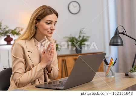 Businesswoman folds hands in prayer laptop looks up hopes for client order or project approval big 132131648