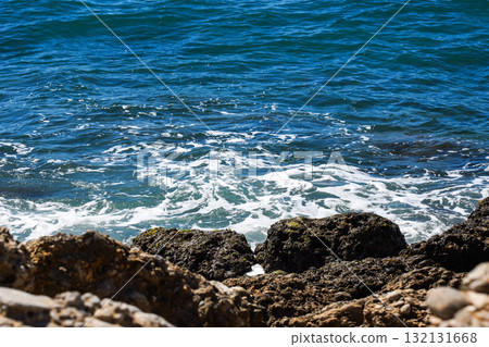 Captivating View of Gentle Waves Interacting with Rocky Shoreline Under Bright Sunny Daylight Captivating View of Gentle Waves Interacting with Rocky Shoreline Under Bright Sunny Daylight 132131668