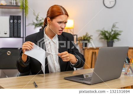 Young businesswoman tears draft report after error then opens new document typing eagerly on laptop 132131694