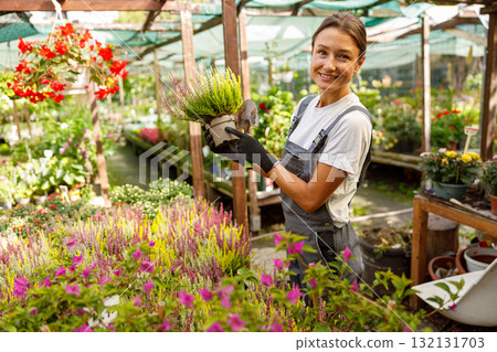 A dedicated woman actively tending to a vibrant greenhouse filled with colorful flowers 132131703