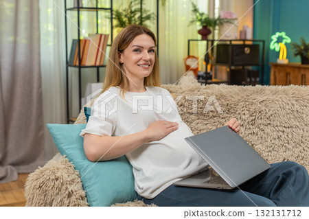Pregnant woman closes laptop exhales relief smiles to camera rubs belly after finishing work shift 132131712