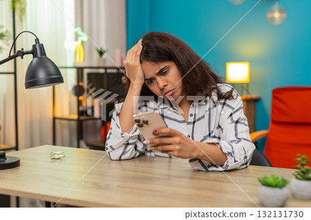 Indian woman upset after bad news on smartphone presses button places phone aside unhappy reaction Indian woman upset after bad news on smartphone presses button places phone aside unhappy reaction 132131730