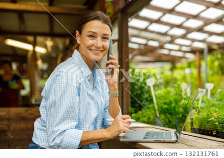 A Woman Skillfully Managing Various Work Tasks in a Greenhouse Environment Setting 132131761