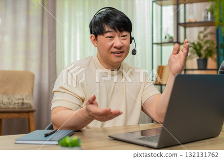 Asian man on laptop headset video call, giving live support with calm tone, online customer service Asian man on laptop headset video call, giving live support with calm tone, online customer service 132131762