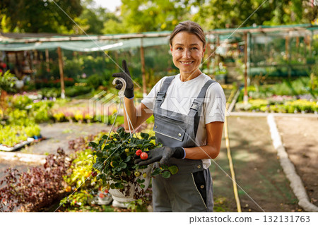 A joyful gardener surrounded by vibrant hanging plants in an abundant and lush garden setting 132131763