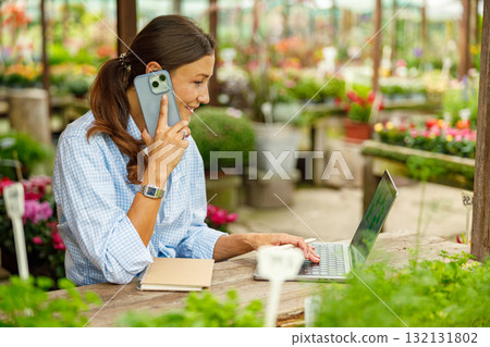 A Woman Engaged in Working Remotely Amidst a Lively and Beautiful Greenhouse Environment 132131802