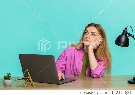 Adult woman working at laptop at table leaning on hand showing tired face and fatigue from long task 132131821
