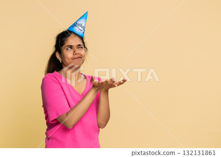 Indian woman smiling holding imaginary cake, joyfully blowing candle, happily making birthday wish Indian woman smiling holding imaginary cake, joyfully blowing candle, happily making birthday wish 132131861