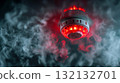 Ceiling smoke detector activated with glowing red light surrounded by dense swirling smoke creating a clear fire alarm and emergency warning scene. 132132701