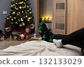 Horizontal photo of cozy home interior with Christmas tree, festive gnomes, and people relaxing in warm socks. Symbol of comfort, winter spirit, and holiday warmth 132133029