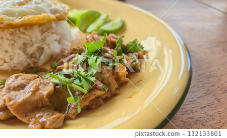 Closed up of Pork stir-fried with garlic and peppercorns with fried egg served with rice and cucumber slices on plate Closed up of Pork stir-fried with garlic and peppercorns with fried egg served with rice and cucumber slices on plate 132133801