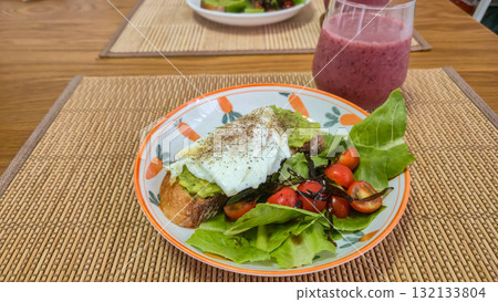 Poached egg and avocado toast with fresh salad and berry smoothie on wooden table Poached egg and avocado toast with fresh salad and berry smoothie on wooden table 132133804