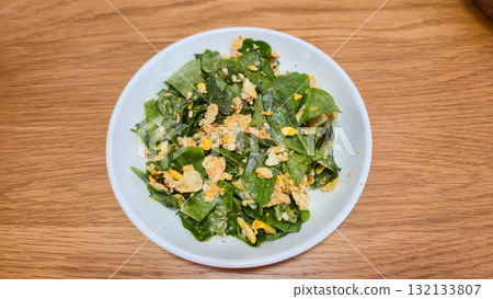 Stir-fried Malindjo Leaves with Egg on white plate on wooden table Thai food Stir-fried Malindjo Leaves with Egg on white plate on wooden table Thai food 132133807