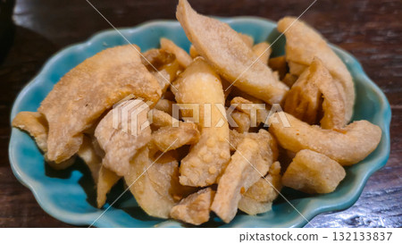Close-up of crispy pork rinds in a blue bowl on wooden table Close-up of crispy pork rinds in a blue bowl on wooden table 132133837