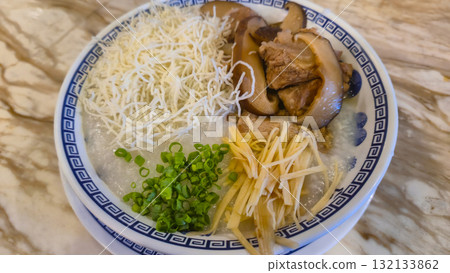 Bowl of savory rice porridge with mushrooms, shredded chicken, and green onions on marble table Bowl of savory rice porridge with mushrooms, shredded chicken, and green onions on marble table 132133862