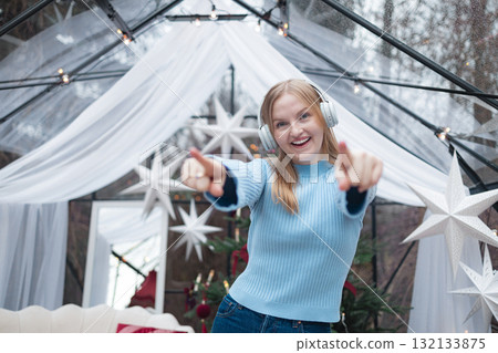Cheerful blonde Caucasian woman dancing and pointing at camera in festive Christmas interior Cheerful blonde Caucasian woman dancing and pointing at camera in festive Christmas interior 132133875