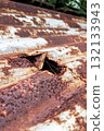 Close-up of rusty corrugated metal sheet with a hole, corrosion texture and decay detail 132133943