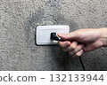 a hand pulling the plug out of an outlet 132133944