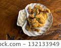 Breaded shrimp on a plate with white garlic sauce, on a wooden surface 132133949
