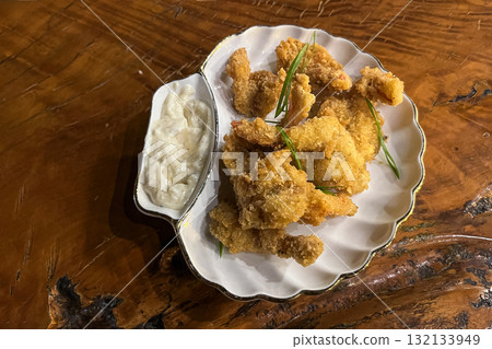 Breaded shrimp on a plate with white garlic sauce, on a wooden surface 132133949