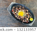 Sizzling pork sisig, a Filipino skillet dish served on a wooden tray with calamansi 132133957