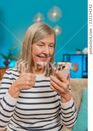 Mature woman celebrating online lottery win victory on smartphone, happily viewing good news at home Mature woman celebrating online lottery win victory on smartphone, happily viewing good news at home 132134142