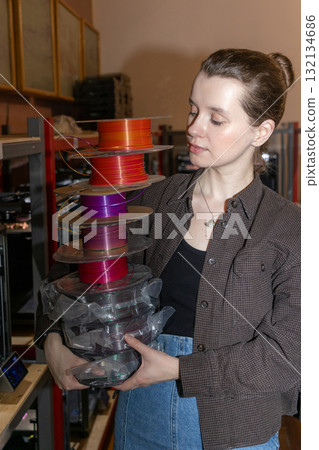 female engineer carries a plastic wire for a 3D printer in her hands. 132134686