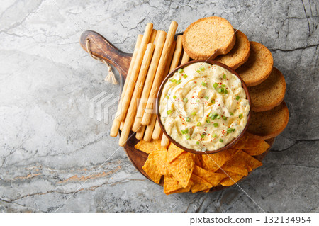 Deviled Egg Dip appetizer for a buffet or picnic with nachos, breadsticks and toast close-up on a wooden board. Horizontal top view 132134954