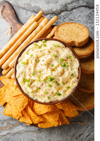 Tasty Deviled Egg Dip with nachos, breadsticks, and toast close-up in a plate. Vertical top view 132134959