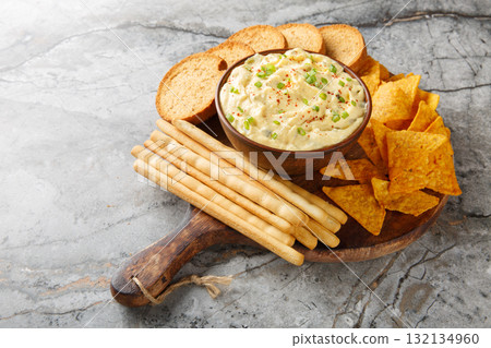 Deviled Egg Dip appetizer for a buffet or picnic with nachos, breadsticks and toast close-up on a wooden board. Horizontal 132134960