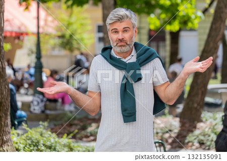 Confused mature man having doubts no idea being clueless uncertain feeling embarrassed, city street 132135091