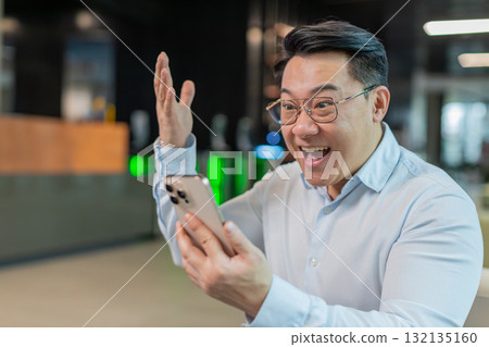 Happy amazed businessman using smartphone shocked by sudden victory lottery win in office lobby Happy amazed businessman using smartphone shocked by sudden victory lottery win in office lobby 132135160