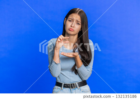Woman showing a little bit gesture with sceptic smile showing minimum sign measuring small size 132135186