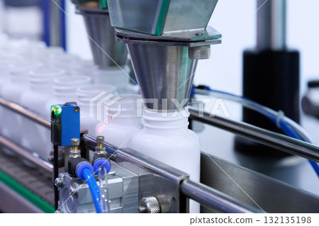medicine pill capsules are filling in the white plastic bottle on production line machine conveyor at the medical factory. 132135198