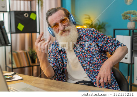 Happy senior man listening music through wireless headphones relaxing taking a break with laptop Happy senior man listening music through wireless headphones relaxing taking a break with laptop 132135231