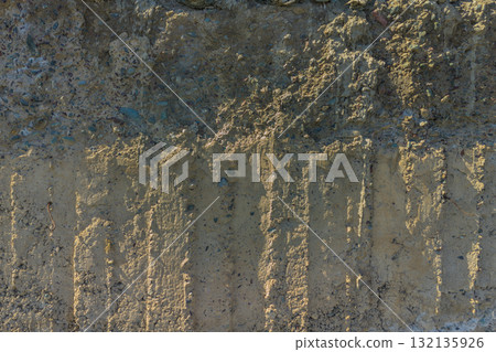 Weathered Cheap Uneven Concrete Surface with Pebbles under tangential harsh light Weathered Cheap Uneven Concrete Surface with Pebbles under tangential harsh light 132135926