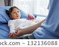 asian girl patient lying in hospital bed with bandaged hand and IV line, holding hands with nurse, doctor, medical professional or father. healthcare with compassion, trust and emotional support. 132136088