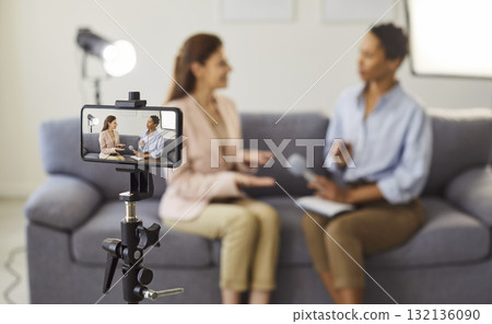 Smartphone camera on tripod framing two women in a candid interview scene Smartphone camera on tripod framing two women in a candid interview scene 132136090