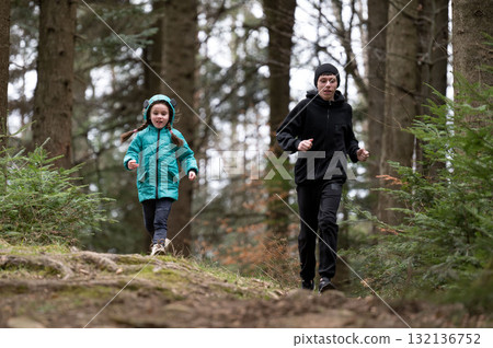Two children enjoy a brisk run through a lush woodland trail on a cool, overcast day, cultivating a spirit of adventure in the heart of nature Two children enjoy a brisk run through a lush woodland trail on a cool, overcast day, cultivating a spirit of adventure in the heart of nature 132136752