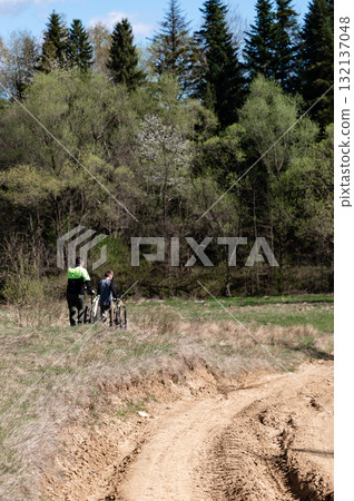 Two cyclists pause their ride, enjoying the tranquil forest scenery. Two cyclists pause their ride, enjoying the tranquil forest scenery. 132137048