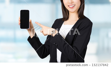 A woman/businesswoman pointing at a smartphone screen 132137842